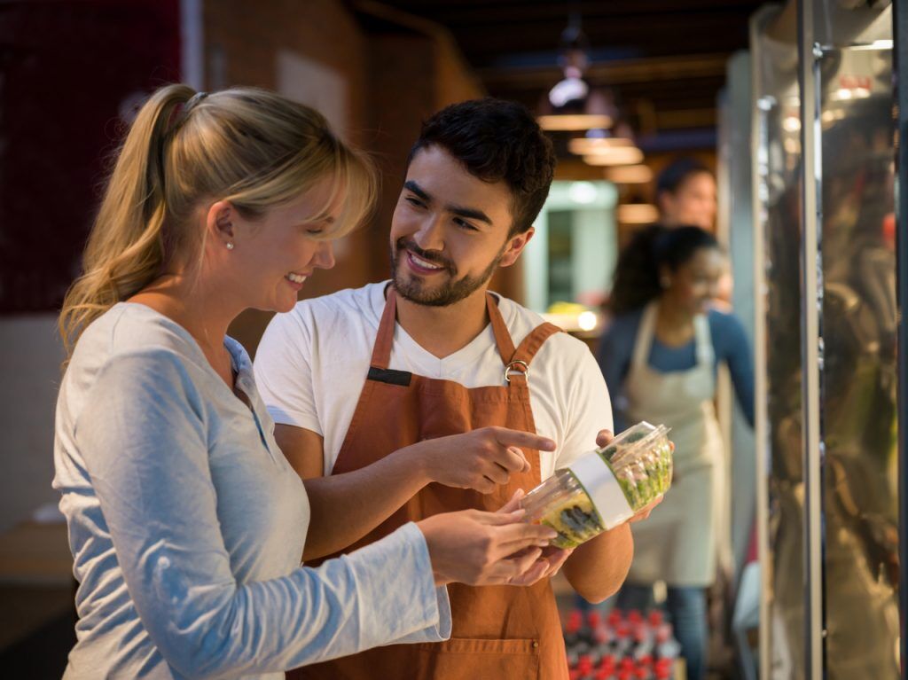 Cheerful salesman suggesting a new salad to a beautiful customer