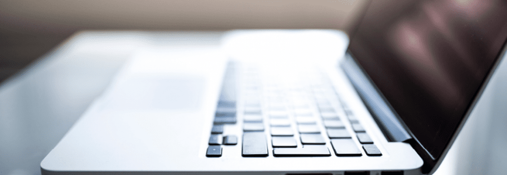 An open laptop sits in front of a sunny window